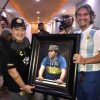 Diego Maradona standing next to portrait by Fabian Perez