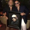 Pitbull standing next to portrait by Fabian Perez