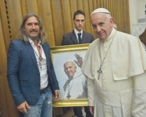 Pope Francis standing next to portrait by Fabian Perez