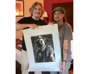 Phil Campbell standing next to portrait by Fabian Perez