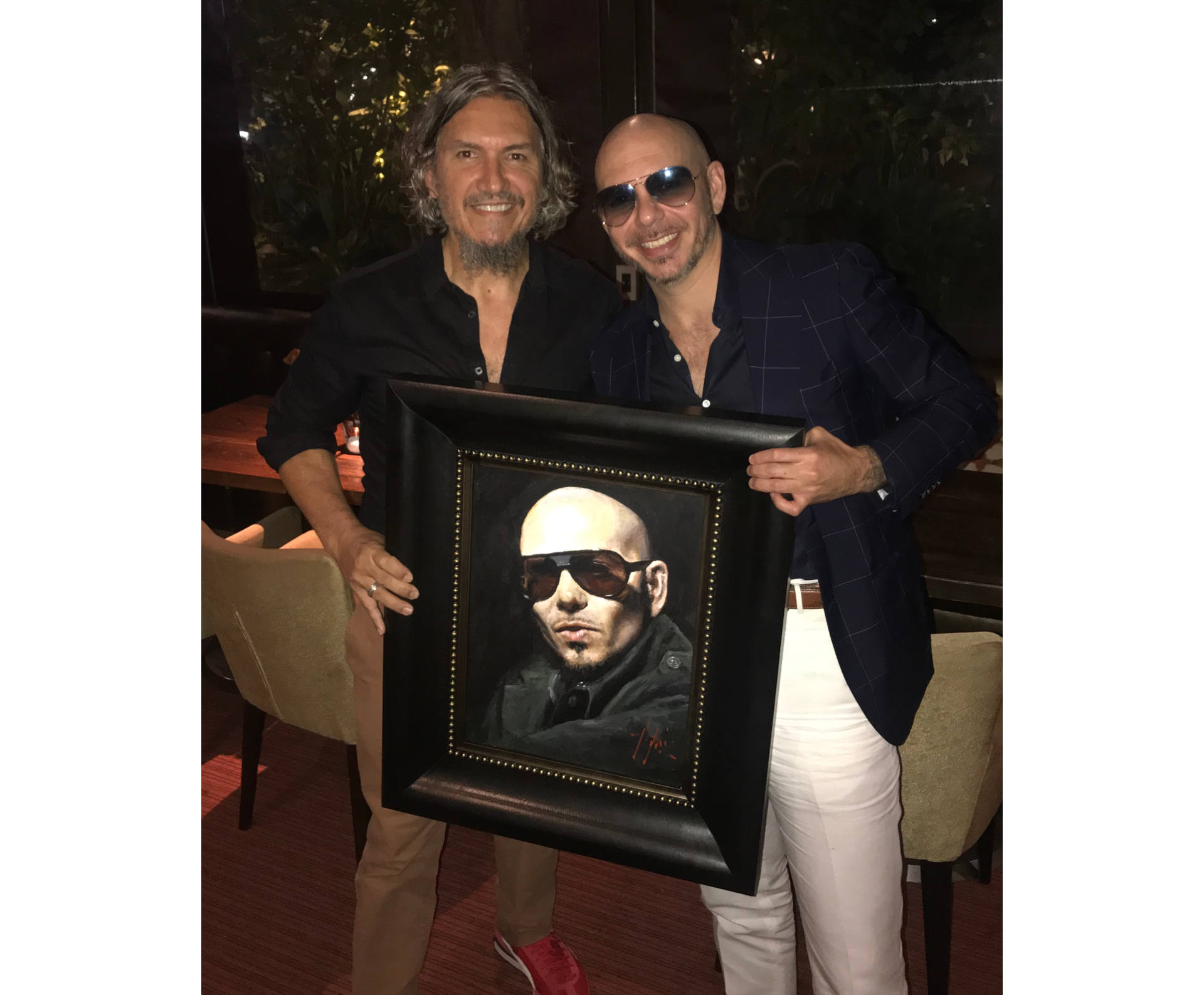 Pitbull holding portrait next to painter Fabian Perez
