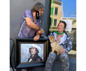 Mickey Rourke sitting next to portrait alongside painter Fabian Perez